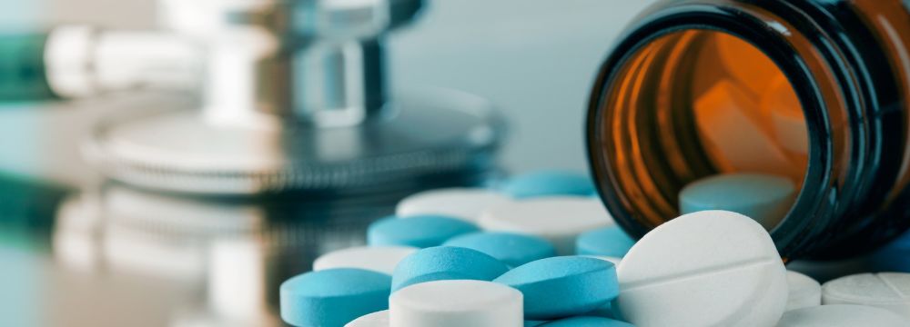 Blue and white pills spilling out of bottle on counter